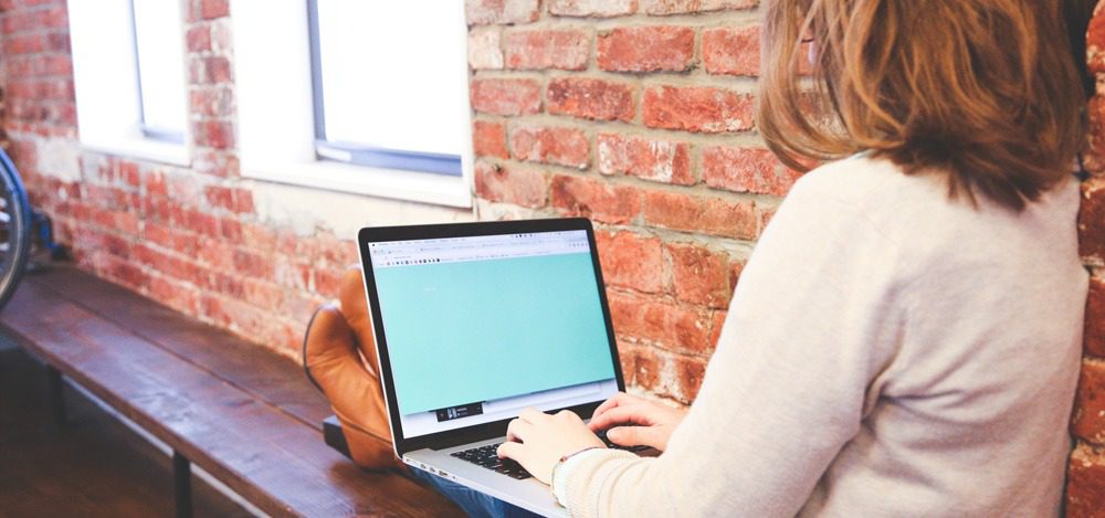 Think Cirrus/small business owner/a person on a laptop with a brick wall in the back ground