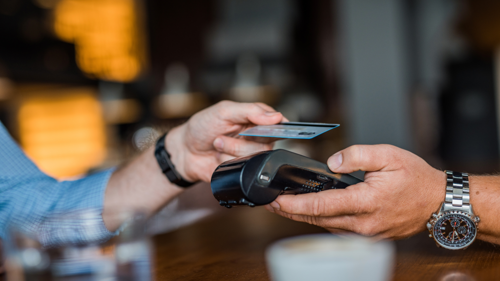 Staff member processing a card payment on a restaurant EPOS terminal during service. importance of technology in hospitality.
